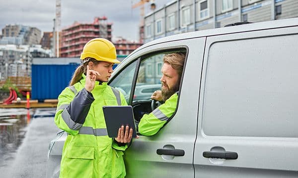Kvinde med en tablet taler med en mand på byggepladsen