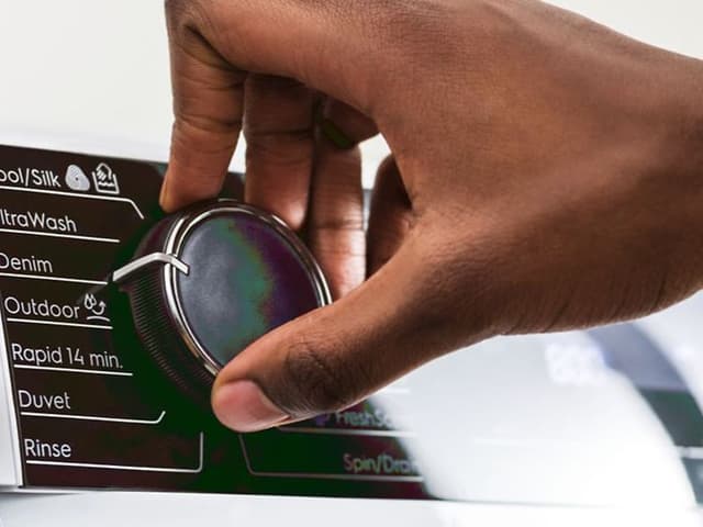 En hånd som holder på programvelgeren på en Electrolux vaskemaskin