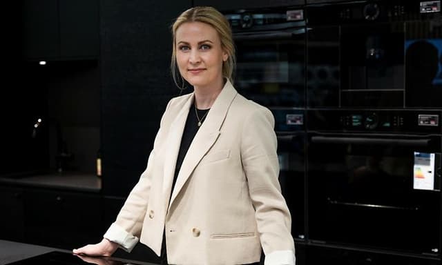Interiørdesignekspert og seniordesigner Ingvill Greve Hermansen hos Epoq står foran et Epoq-kjøkken i en butikk