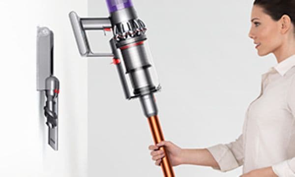 Nainen asettaa Dyson V10 Parquet -imurin lataustelakkaan
