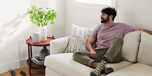 Man sittin in a white sofa while listening to something on his Google Nest Audio
