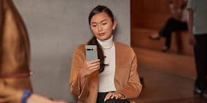 Kvinde sidder ved et café-bord mens hun kigger på sin Pixel telefon