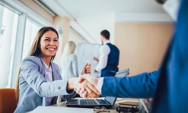 Kvinne håndhilser med person i blå dress