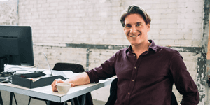 B2B - Android Zero-Touch - A smiling young man in a rustic office space 1000x500