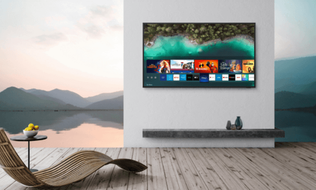 Samsung The Terrace på en vägg med en solstol bredvid med utsikt mot en sjö och berg efter solnedgång
