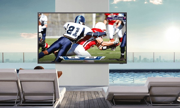 En Samsung The Terrace TV som viser en amerikansk fotballkamp utendors med sterk sol i bakgrunnen