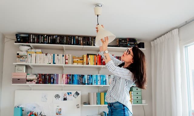 Kvinde skifter pære i lampe