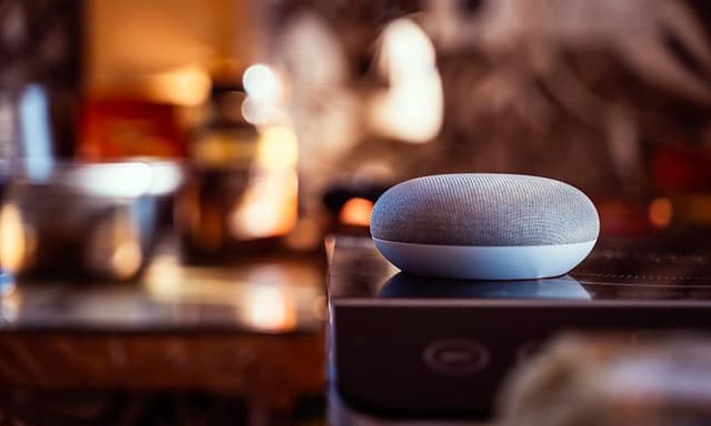 Google Home Mini/Nest placerad på ett bord med suddig bakgrund