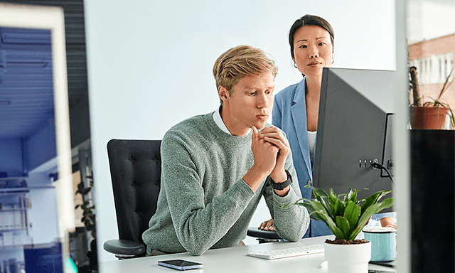 Person lutad mot ett bord som använder telefon med laptop bredvid sig