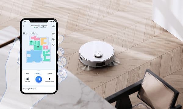 T10 Plus på ett ljust trägolv vid en stol med en illustrerad hand som håller en smartphone som visar den tillhörande appen