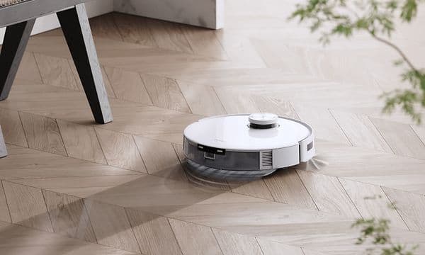 T10 Plus dammsuger ett ljust trägolv vid en stol och en planta