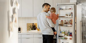 Mies vauva sylissään jääkaapilla