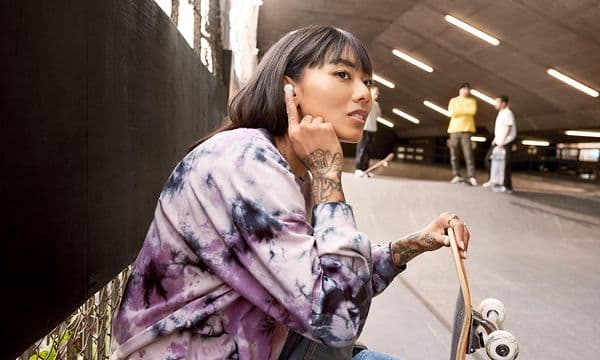 Woman with skateboard taping on Pixel Buds