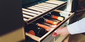 Man taking wine bottles from a wine cooler