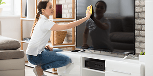 Rengjøring av tv-skjerm med en mikrofiberklut.