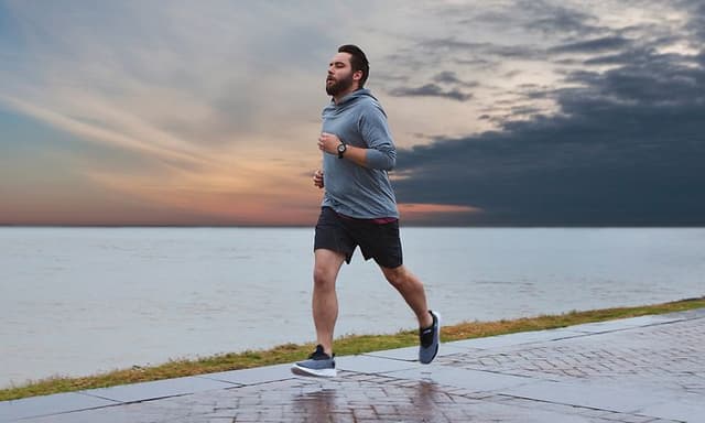 En mann som jogger ved havet med en Garmin Forerunner sportsklokke