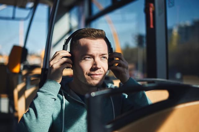 En mand i en bus i færd med at tage headset på.