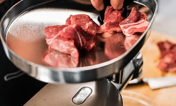 Man som lägger kött i en köttkvarn