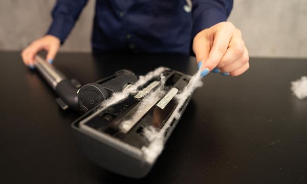 Woman cleaning the mouthpiece of a vacuum cleaner