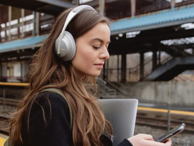 Kvinde på perron med noise cancelling høretelefoner