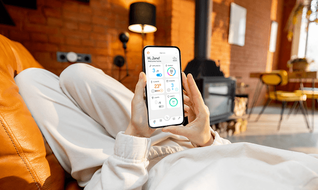 Person i koseklær som får oversikt over strømforbruket på telefonen med Futurehome-appen