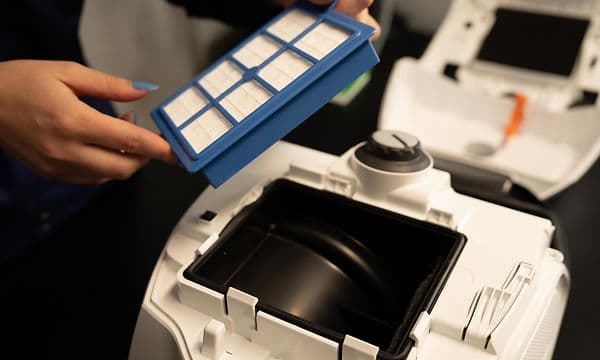 En kvinde fjerner støvsugerfilter fra støvsuger