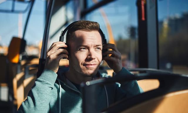 Man on a bus putting on headphones