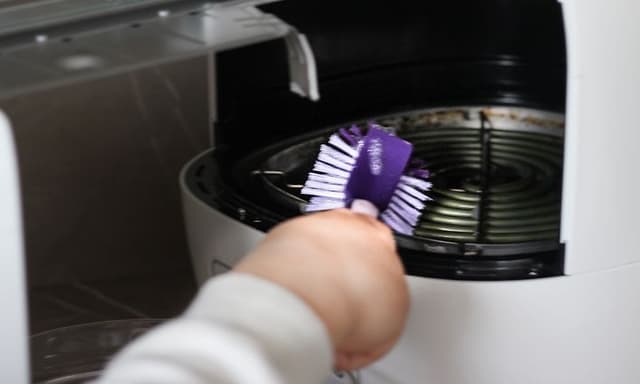 SDA - Airfryer - Person cleaning an airfryer with a purple brush