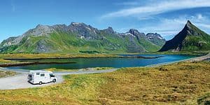 Billede af en autocamper foran en sø og bjerge