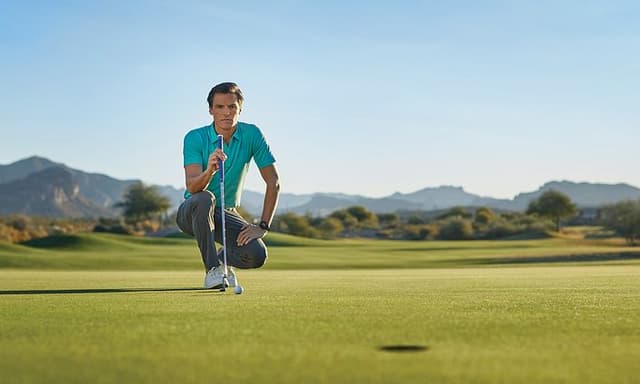 En mand på knæ på en golfbane med en golfkølle i hånden