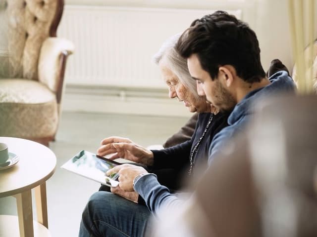 Man and old woman looking at a tablet