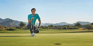 Mannlig golfspiller på golfbane med en Garmin Approach golfklokke på armen