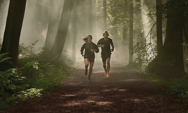 Kvinne og mann som løper i skogen med hver sin Garmin Forerunner smartklokke på armen