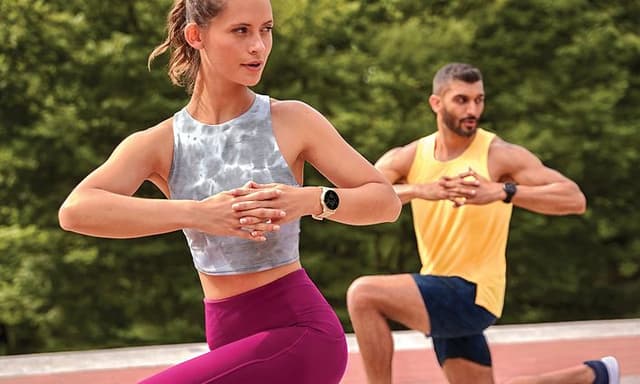 En kvinne og en mann som trener yoga med hver sin Garmin Venu smartklokke rundt håndleddet