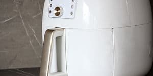 Närbild av en vit airfryer på en svart köksbänk