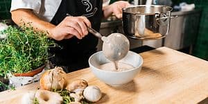 Kokki kaataa kasviskeittoa kulhoon