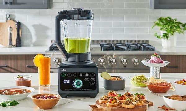 Tehosekoittimessa vihreää smoothieta ja pöydällä muita herkkuja
