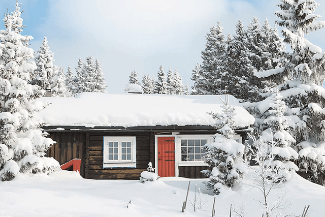 en hytte dekket av snø i et vinterlandskap