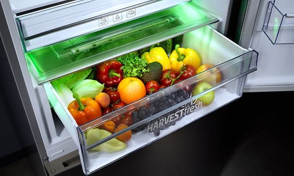 An open fridgedrawer with the HarvestFresh-logo full of vegetables