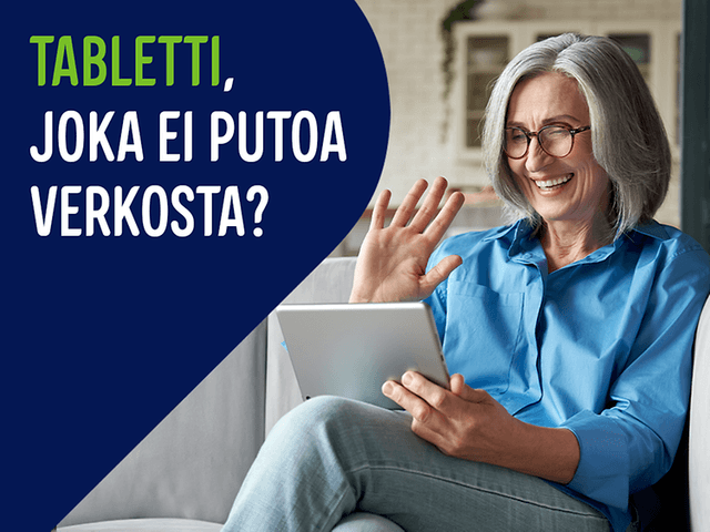 Nainen istuu sohvalla ja hymyilee tablettia katsoen