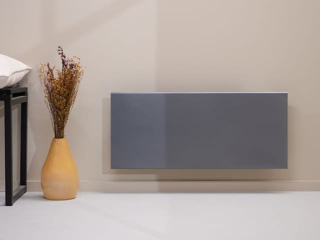 Grå Adax Neo panelovn på beige vegg