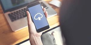 Telecom - skift fra iPhone til Android - Person der holder en telefon i hånden der downloader fra skyen