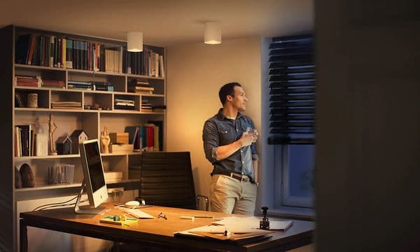 Mies katsoo ulos himmeästi valaistusta työhuoneesta