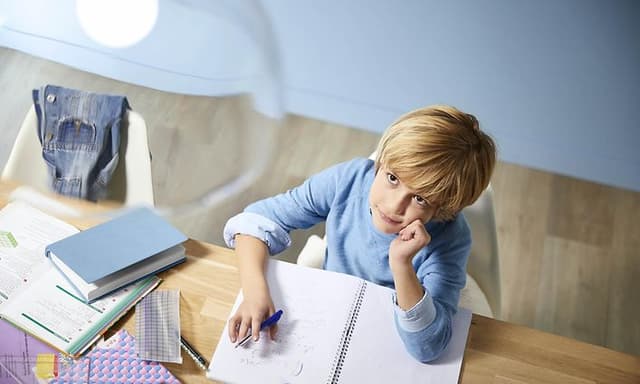 Kid doing homework and looking up on a lamp with Philips Eyecomfort LED bulb