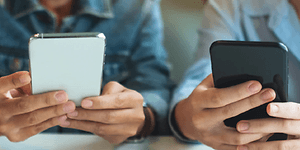Telecom - skift telefoner - To teenagere der bruger deres telefoner ved et bord