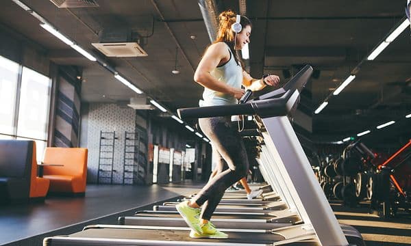 Telecom - Wearables - Woman checking her watch on a treadmill