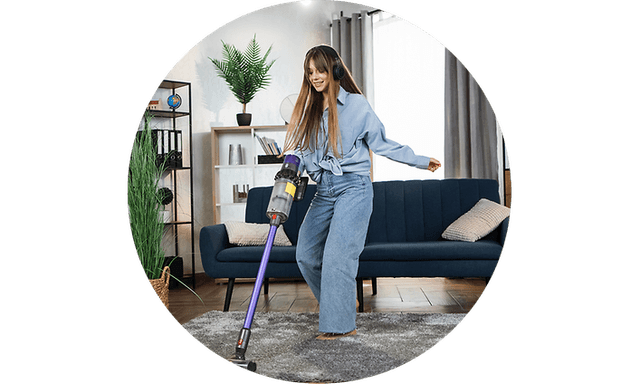 A girl vacuums a room with headphones on