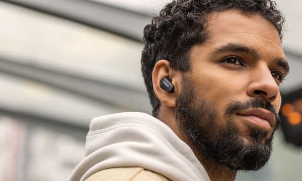 Huppariin pukeutunut mies kuuntelee Bose Earbuds -nappikuulokkeilla