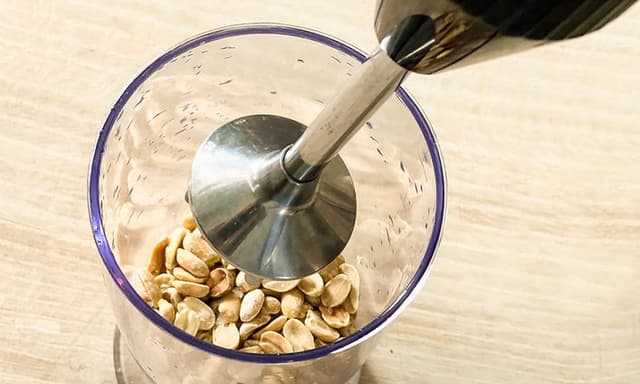 Köksapparater: En stavmixer som används för att hacka jordnötter i en mixerkopp.