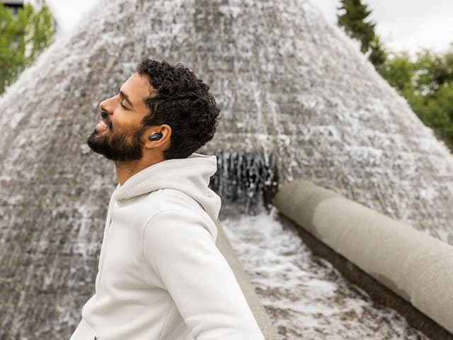 Mand iført en hoodie med Bose Earbuds i ørerne